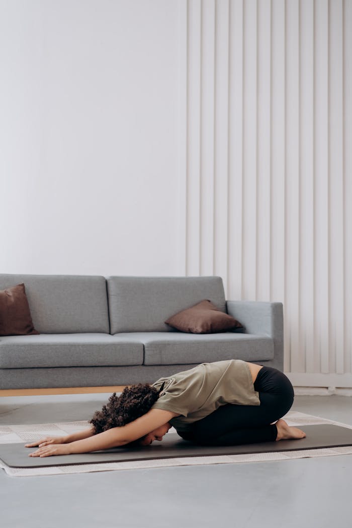 Young woman practicing yoga at home, fostering relaxation and inner peace in a serene living room setting.